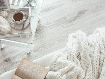 still life details, cup of tea on retro vintage wooden tray on a coffee table in living room, top view point. lazy winter weekend with a book on the sofa.