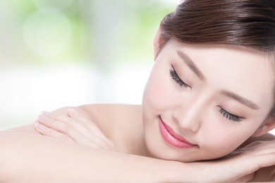 charming woman face smile enjoy spa and massage while lying with green background, asian girl