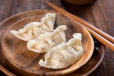 close up fresh boiled dumplings with hot steams on wood plate. chinese food on rustic old vintage wooden background. 