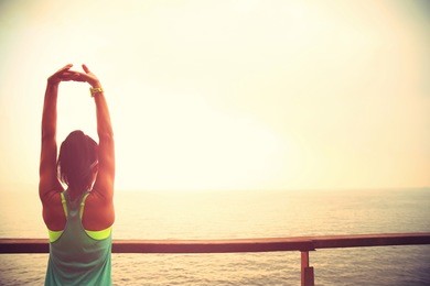 fitness sports woman runner stretching on wooden boardwalk seaside