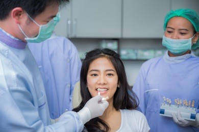 smiling asian woman with palette for tooth color