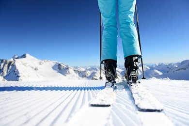 girl on ski standing on the fresh snow on newly groomed ski piste at sunny day in mountains