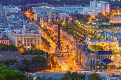 aerial view over square portal de la pau, and port vell marina and columbus monument at night in barcelona, catalonia, spain