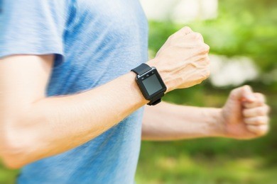 male runner jogging outside with his smart watch at sundown