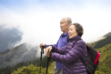 happy asian senior couple hiking on the mountain