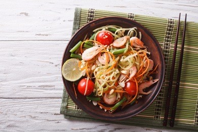 thai green papaya salad with shrimp on a plate on the table. horizontal view from above