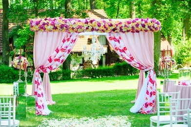 pink wedding arc with roses and peonies like decoration for elegant wedding ceremony in the garden