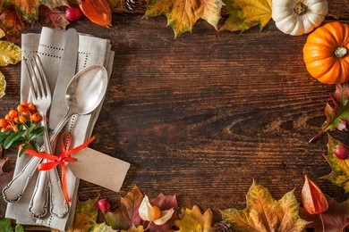thanksgiving autumn place setting with cutlery and arrangement of colorful fall leaves