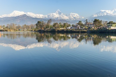 lake phewa in pokhara, nepal, with the himalayan mountains in the background, including machhapuchhre and annapurna