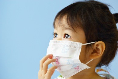 asian little girl gets sick on blue background.