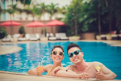 happy couple in sunglasses spending vacation in swimming pool