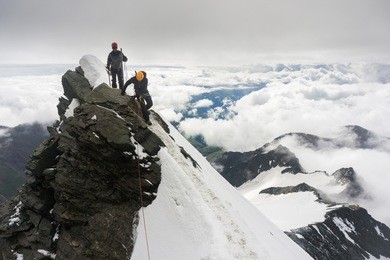 mountaineers climbing grossglockner, austria, on the final snow ridge