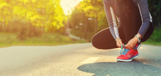 female runner tying her shoes preparing for a run a jog outside 
