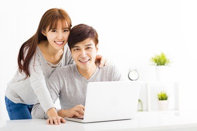 happy young couple with laptop in living room