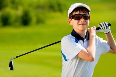portrait of boy golfer in golf course at summer day