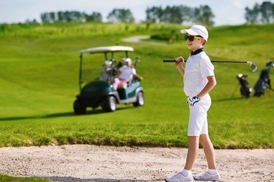 boy playing golf and hitting from bunker 