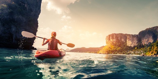 lady paddling the kayak in the calm tropical bay at sunset