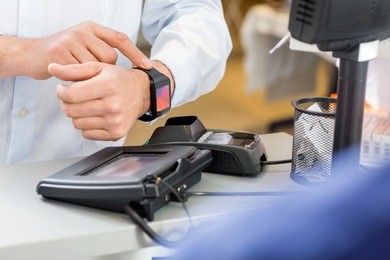 closeup of male customer paying through smartwatch at counter in pharmacy