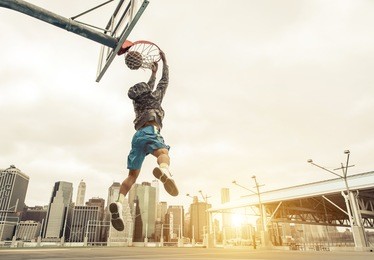 basketball street player making a rear slam dunk. new york and manhattan buildings in the background
