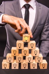 creative idea. young businessman presenting creative idea using wood cubes. studio shooting isolated on black background