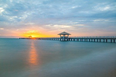 long wood bridge at sea in sunset time