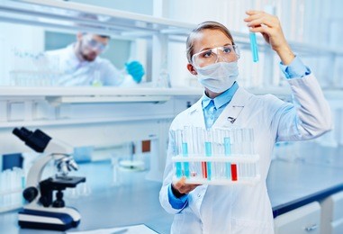 young chemist analyzing liquids in lab on background of colleague