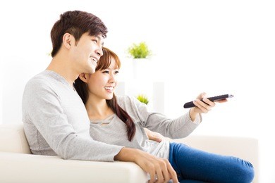 happy young couple watching tv in living room