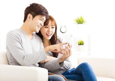 happy  couple looking at smart phone in living room