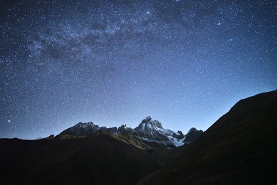 night landscape. starry sky with the milky way over the mountains. mount ushba in the light of the rising moon. main caucasian ridge. zemo svaneti, georgia 