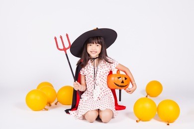 little girl in black hat  with halloween pumpkin 