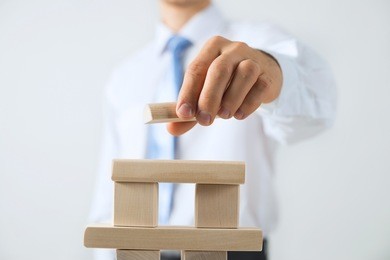 close up of businessman building tower of wooden blocks