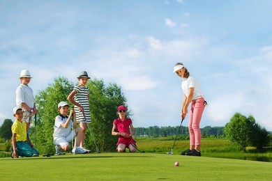 kids playing golf by putter on green