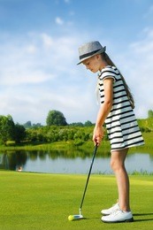 girl playing golf and hitting by putter on green