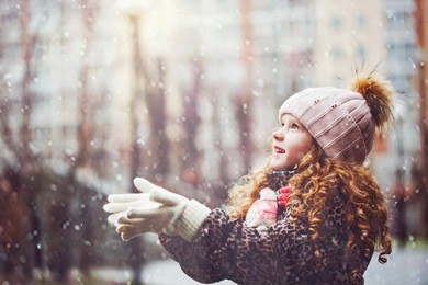 cute little girl stretches her hand to catch falling snowflakes. first snow. toning instagram filter.