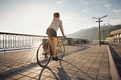 young woman riding a bicycle in the morning city at sunrise