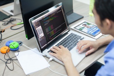 asian developer using laptop computer sitting working real office