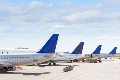 tails of some airplanes at airport during boarding operations. they are four planes on a sunny day, with a blue sky. travel and transportation concepts.