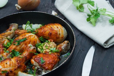 fried chicken drumsticks in a frying pan on wooden table