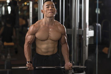 man making effort to lift heavy barbell