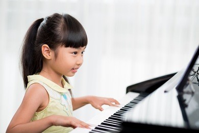 little vietnamese girl playing the piano at home