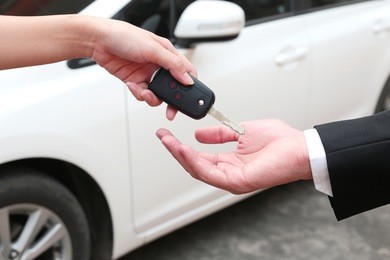 female hand giving a key for buyer or rental car.