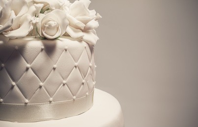 details of a wedding cake, decoration with white fondant on grey background. 