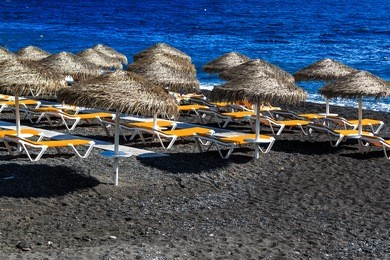 kamari beach of santorini covered with black pebbles, greece island 