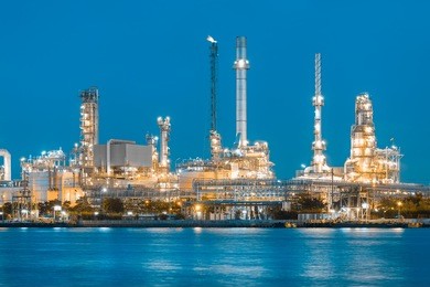 oil refinery reflected on river at twilight.