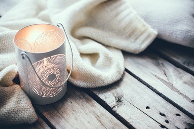 cosy and soft winter background, knitted sweater and candles on an old vintage wooden board. christmas holidays at home.