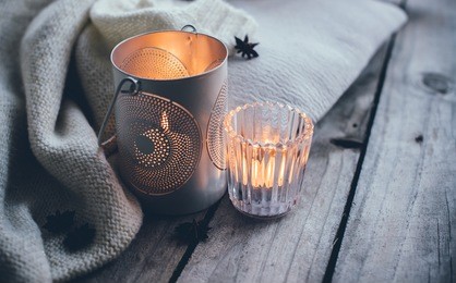 cosy and soft winter background, knitted sweater and candles on an old vintage wooden board. christmas holidays at home.