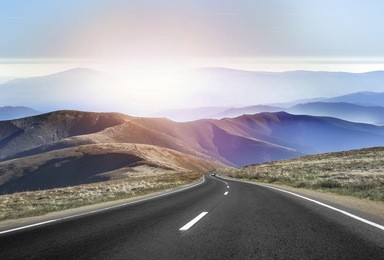 asphalt road in the mountains with soft sky on the background.