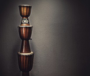 three various wooden djembes in front of an old rusty wall. 