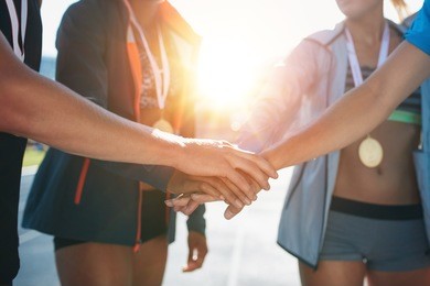 sports people with hands together in huddle. team with hands together celebrating success after winning athletics competition.