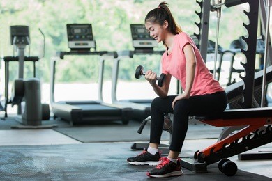 asian women workout lifting a dumbbell in the gym.